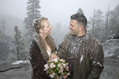 Married couple smile under the falling snow after their wedding