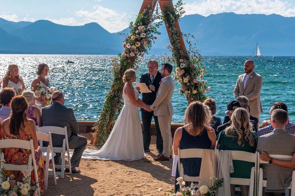 Vows being exchanged at the water's edge under the arch.