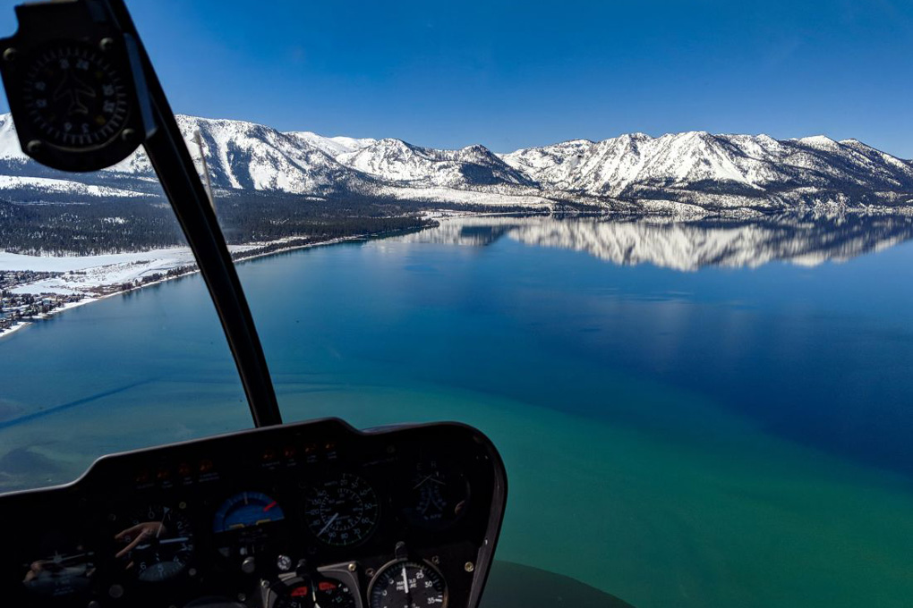 Snow-capped mountains with the lake below as viewed from the helicopter cockpit.