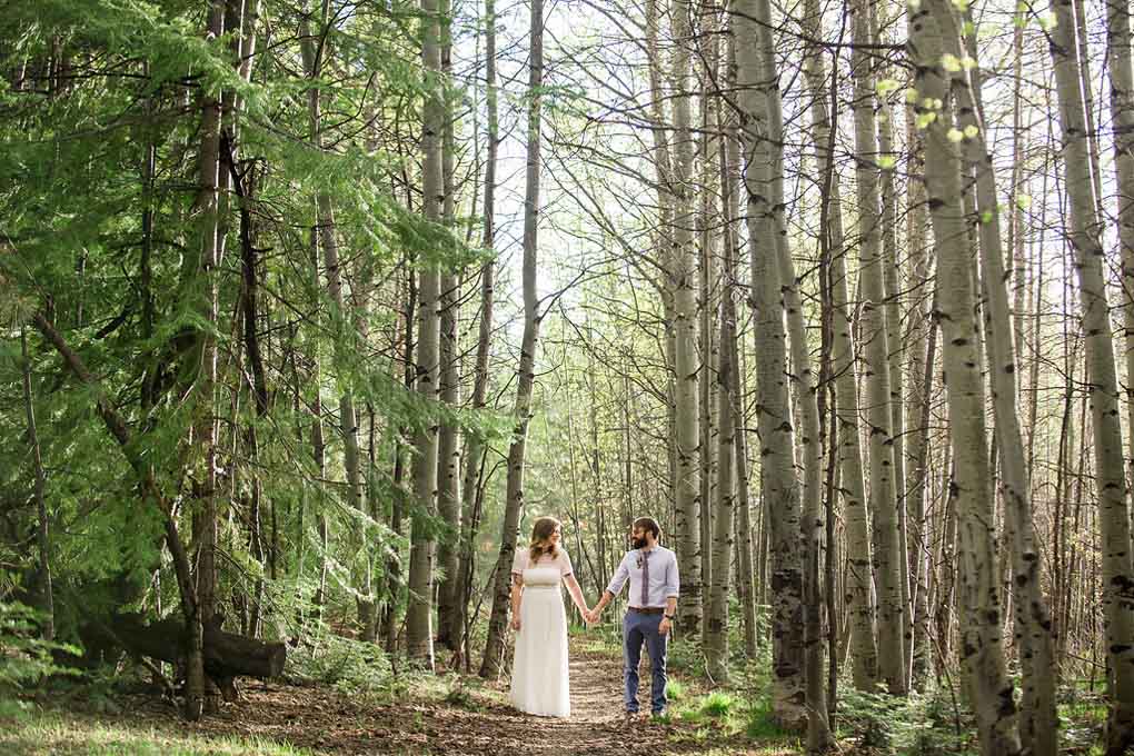 The duo walking on a dirt path among tall tress.