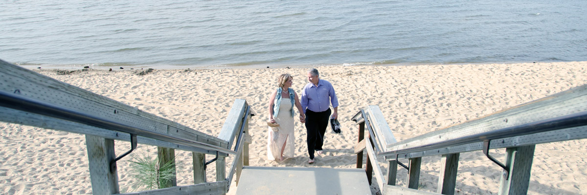 Newlyweds standing at the bottom of the staircase barefooted on the beach.