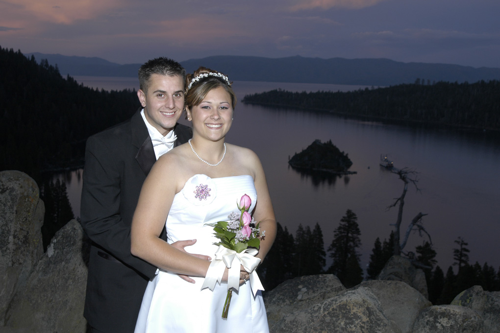 Bride holding her bouquet and the groom wraps his arms around her at Emerald Bat at sunset.