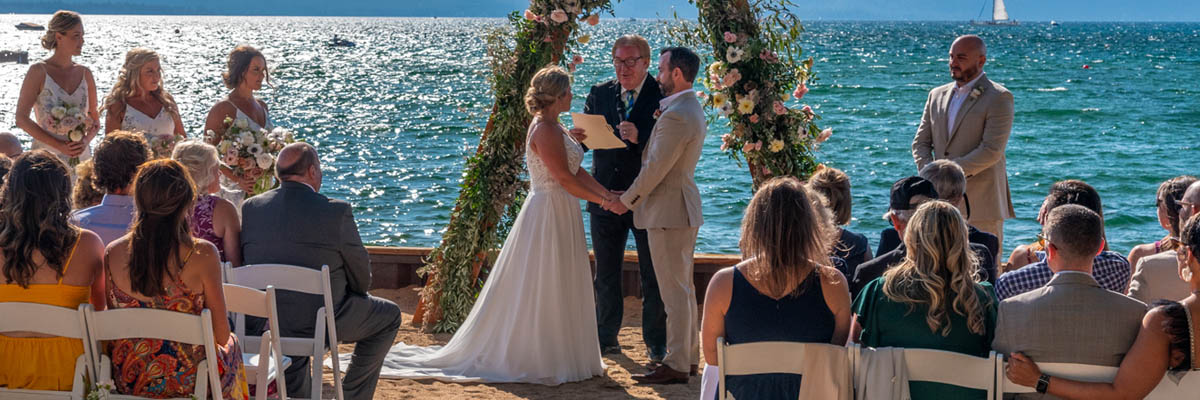 Bridal party standing in front of an arbor as minister conducts the wedding service.