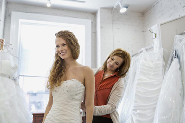 Mom helping her daughter who is trying on her bridal gown.
