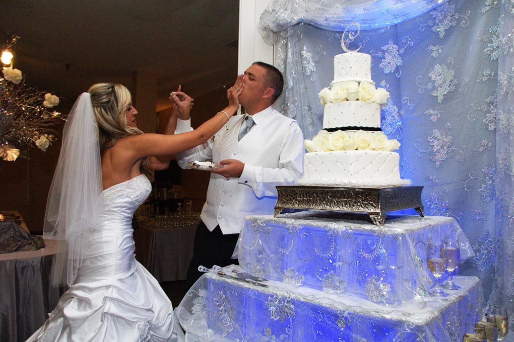 Bride and groom feeding each other a piece of cake at their reception.