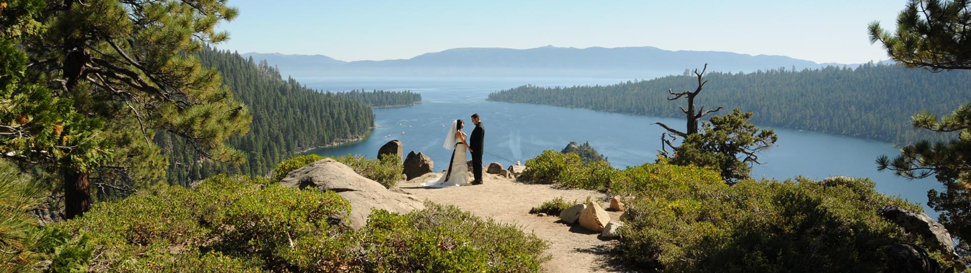 Twosome holding hands at the precipice of Emerald Bay.