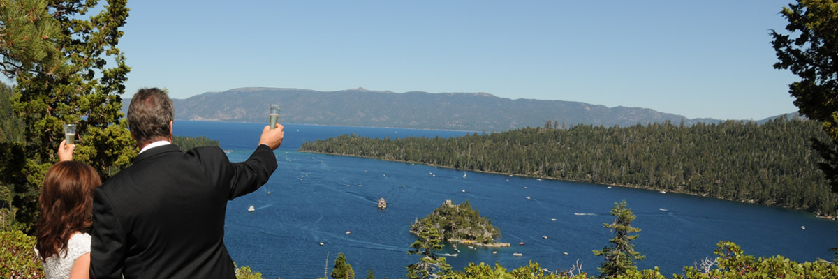 Married couple extending their champagne glasses outward towards Lake Tahoe.