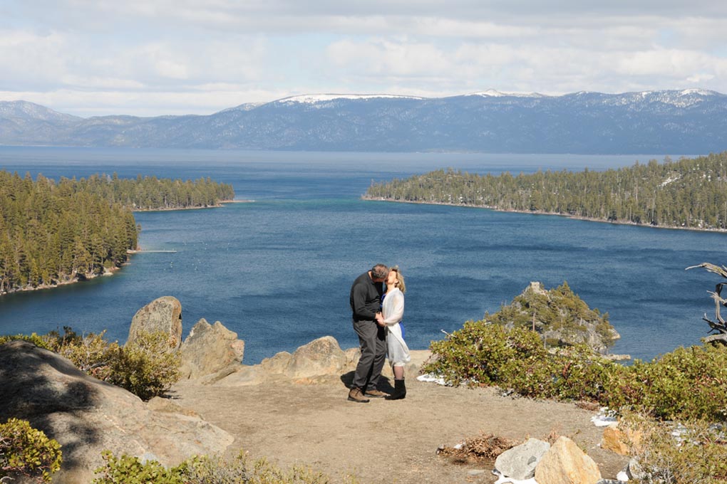 Newlyweds have their first kiss at the edge of the bluff of Emerald Bay.