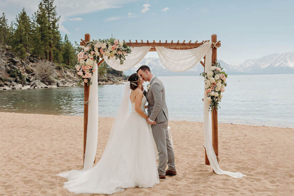 Just married bride and groom have first kiss under the arbor.