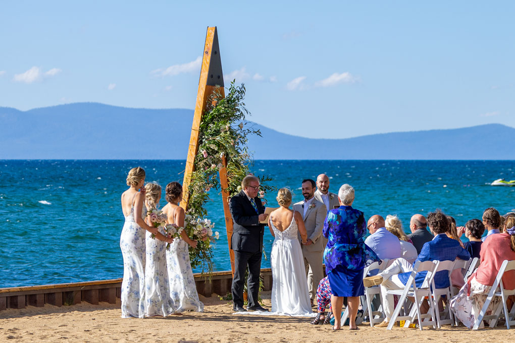 Scenic view of the wedding service performed lakeside in front of the arch with onlooking guests.