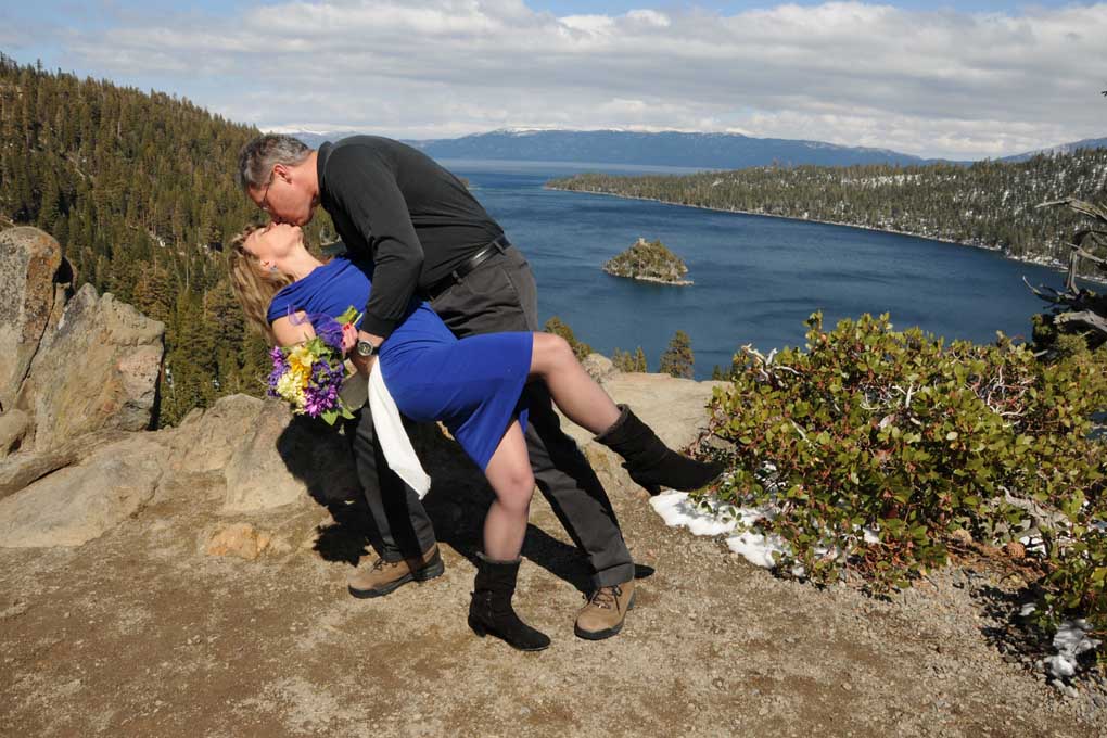 Groom leans his bride backward and gives her a kiss on the overlook at Emerald Bay.