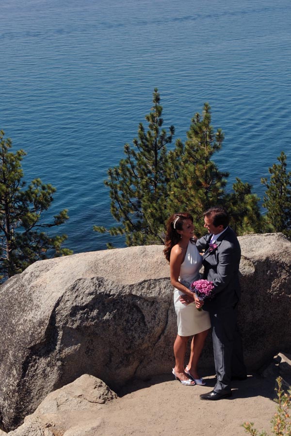 Just married pair gaze lovingly at each other on the nook overlooking Lake Tahoe.