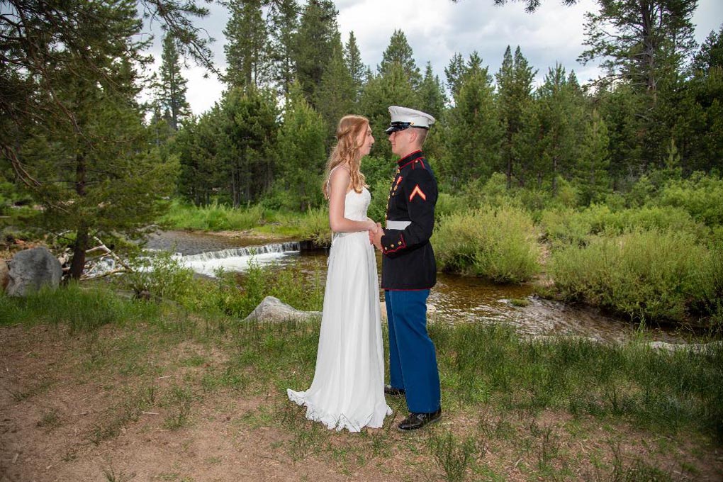 Couple holding hands and facing each other by the river after the marriage ceremony.