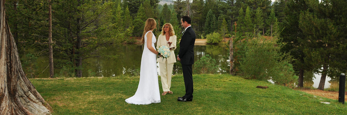 The minister and the marriage participants on the park grass at the edge of Lake Baron.