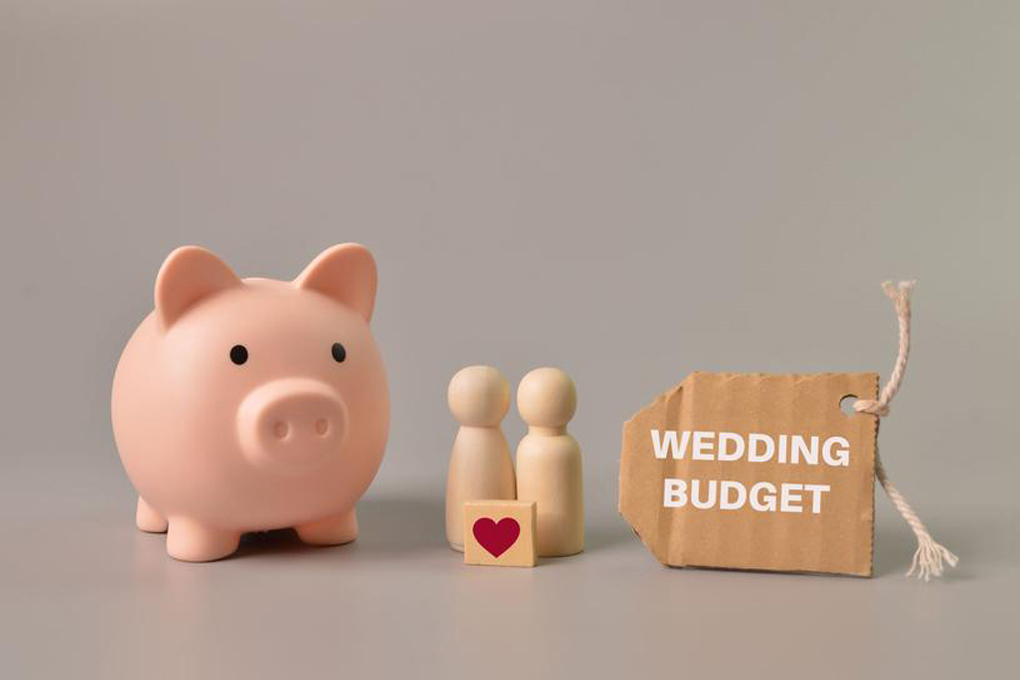 Piggy bank and two figurines next to a wedding budget sign.
