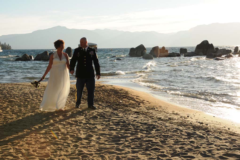 Husband and wife walking along the shoreline hand in hand.