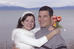Bride wraps her arms around groom's neck while holding her bouquet.