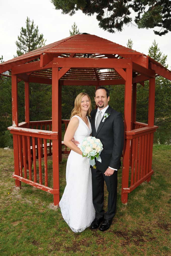 Married couple standing together in front of the park's gazebo.