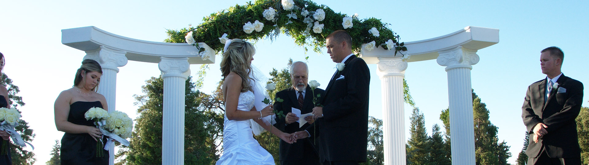 Bride and groom exchanging vows with large white pillars in the background.
