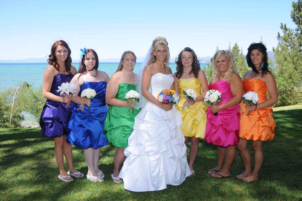 Bride and her bridesmaids pose in very colorful dresses.