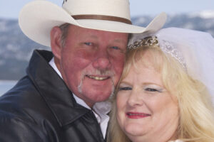 Groom wearing cowboy hat poses with his bride.