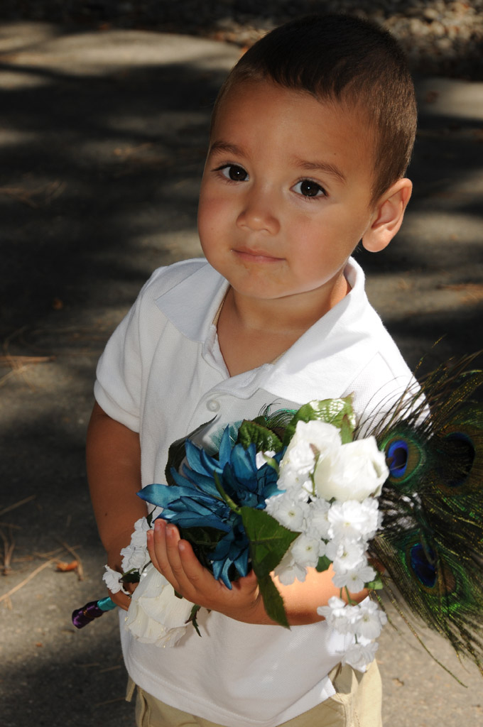 Young boy holding bridal bouquet.