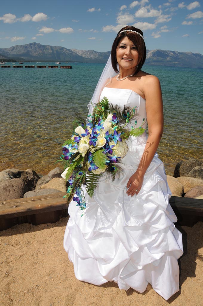The bride by the waterside posing with a large bouquet.