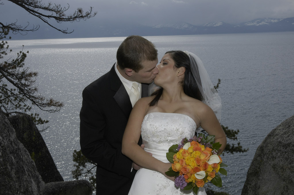 The first kiss as husband and wife in front of a beautiful lake background.