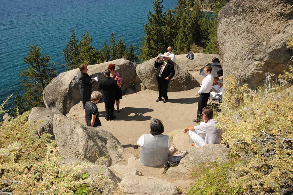 Wedding party and guests gather around the couple during the wedding ceremony taking place at Logan Shoals.