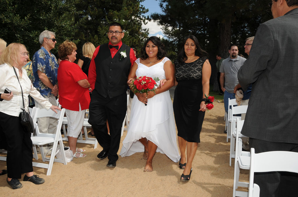 Mother and father of the bride march with her down the wedding aisle.