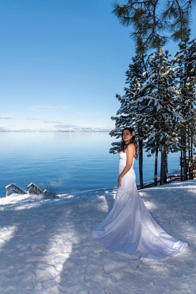 Bride on the snow displays her magnificent gown.