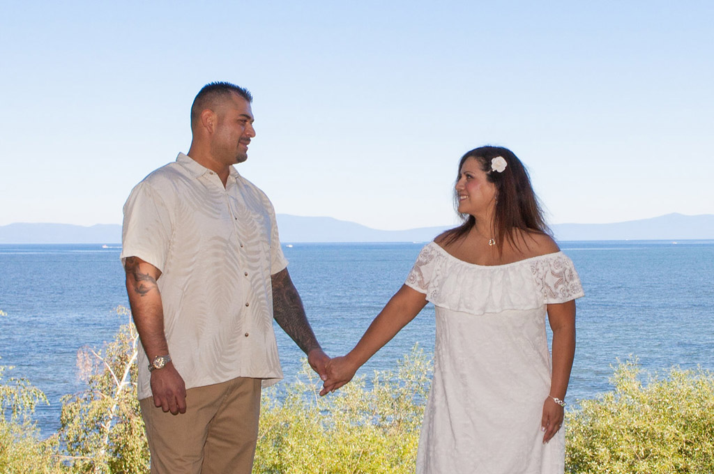 Newly married holding hands with Lake Tahoe in the background.