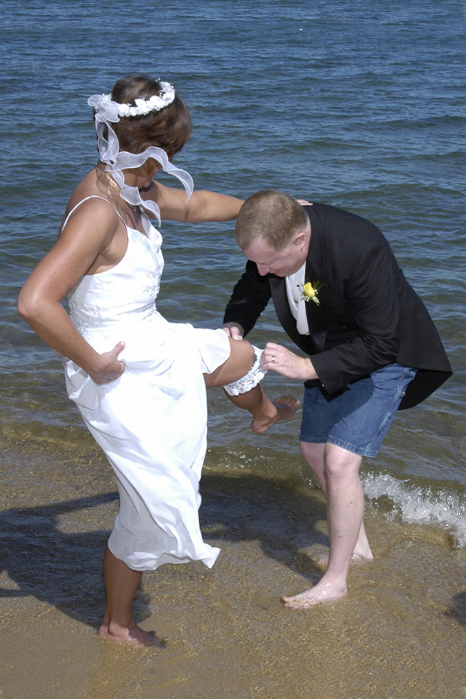 Groom holding his bride's leg as he removes her garter.
