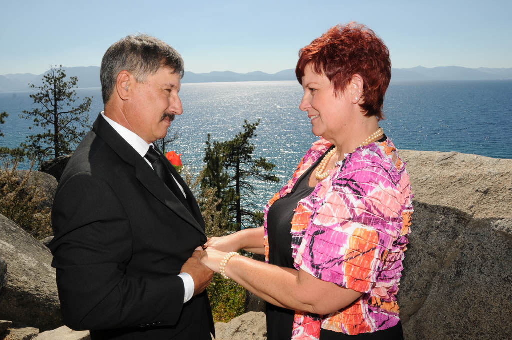Couple facing each other as they hold hands and gaze lovingly into each other's eyes.