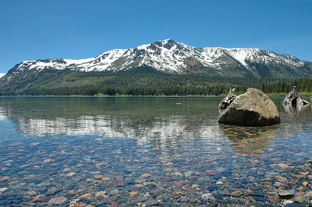 Snowcapped mountain in the background with lake in the foreground.